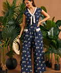 Woman wearing a navy zebra print wide-leg jumpsuit with a contrast tie neckline and patch pockets.