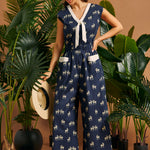 Woman wearing a navy zebra print wide-leg jumpsuit with a contrast tie neckline and patch pockets.