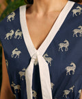 Detail of the V-neckline with white contrast trim and decorative tie on a zebra print jumpsuit.