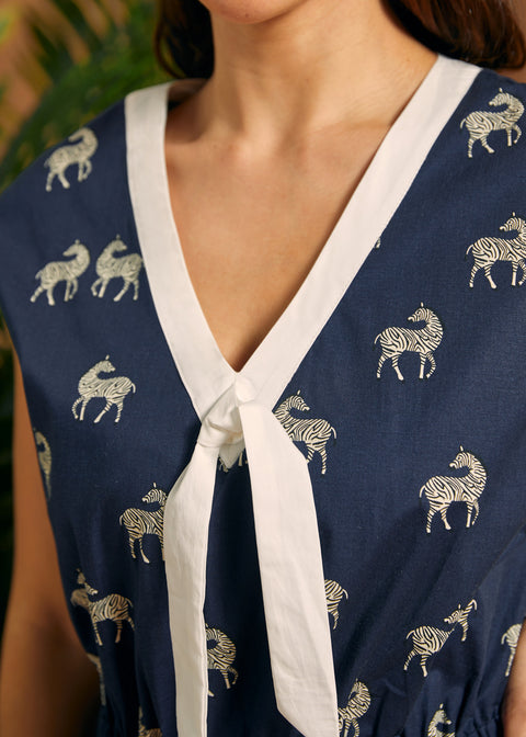 Detail of the V-neckline with white contrast trim and decorative tie on a zebra print jumpsuit.
