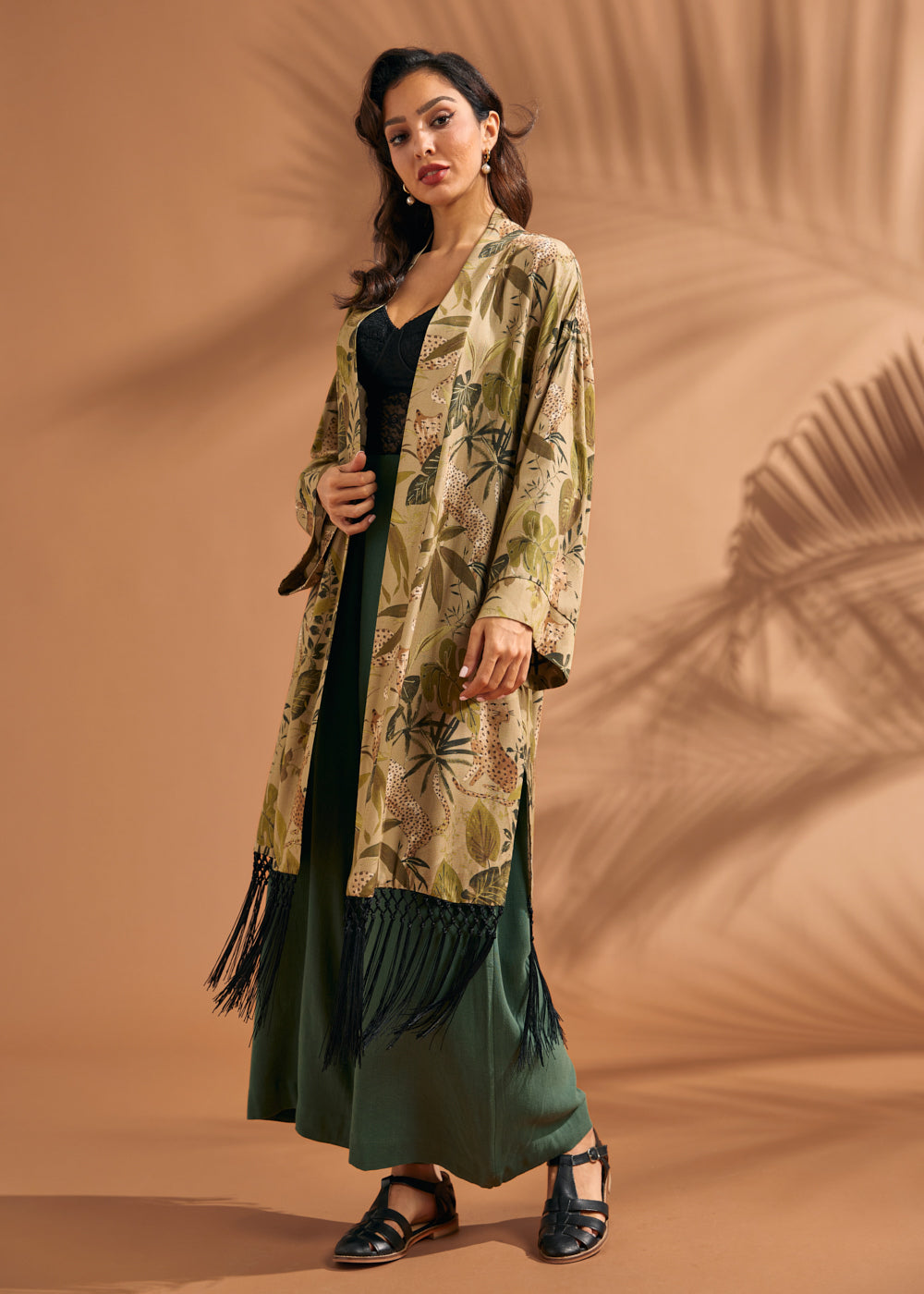 Woman wearing tropical leopard print fringe duster over green wide leg pants.