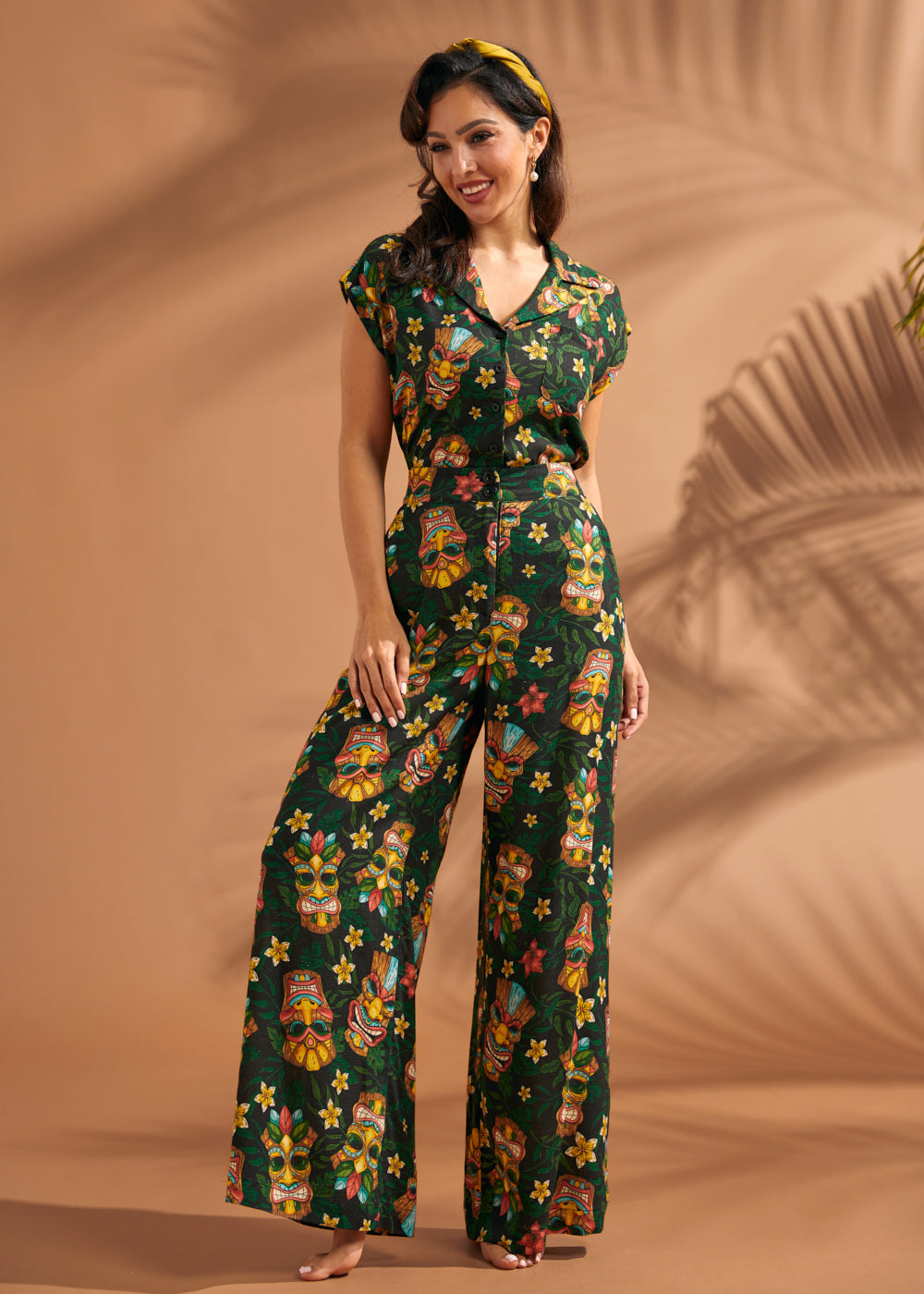 Woman wearing vintage-inspired tropical tiki print wide leg pants with matching top.