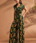 Side angle of woman wearing tropical novelty print wide leg trousers.