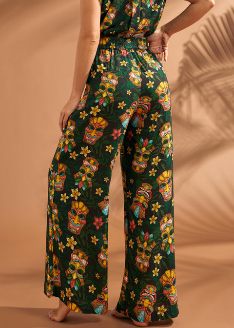 Woman wearing tiki print wide leg pants showing comfortable elastic back waistband.