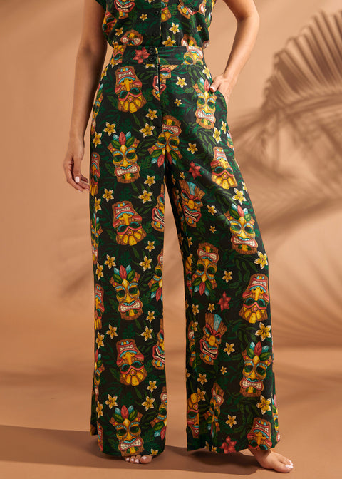 Woman wearing colorful tiki mask print pants with relaxed wide leg silhouette.
