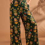 Woman wearing black tropical tiki print wide leg pants with side pockets.