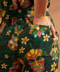 Close-up of colorful tiki mask and floral novelty print on black linen blend trousers.