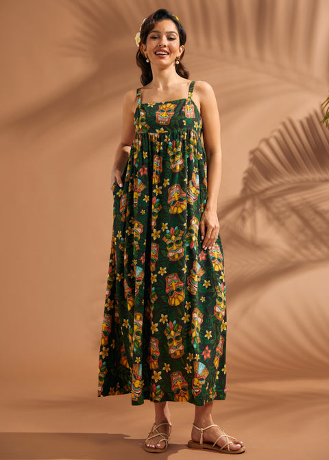 Woman wearing tropical tiki print maxi dress with hidden side pockets and relaxed silhouette.
