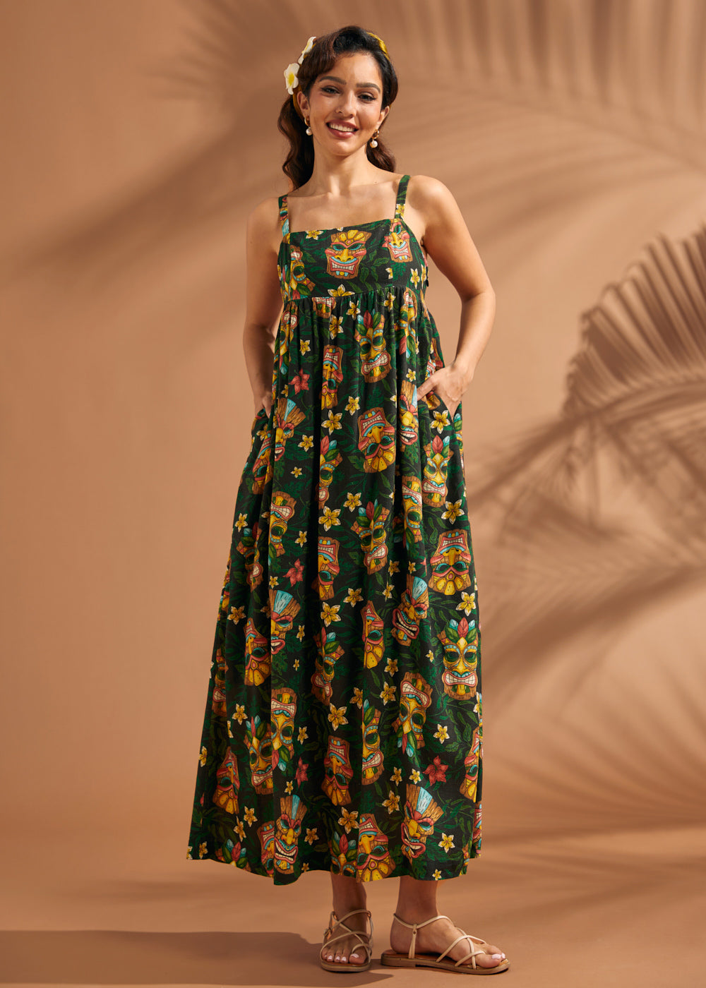 Woman wearing tropical tiki print maxi dress with square neckline and adjustable straps.