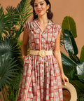 Woman wearing terracotta geometric print midi-inspired shirt dress with pockets.