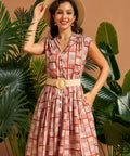 Woman styling belted button front dress with straw hat.