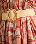 Detail of woven belt and button placket on terracotta print dress.
