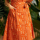 Woman wearing an orange cotton wrap skirt with adjustable tie waist and patch pocket.