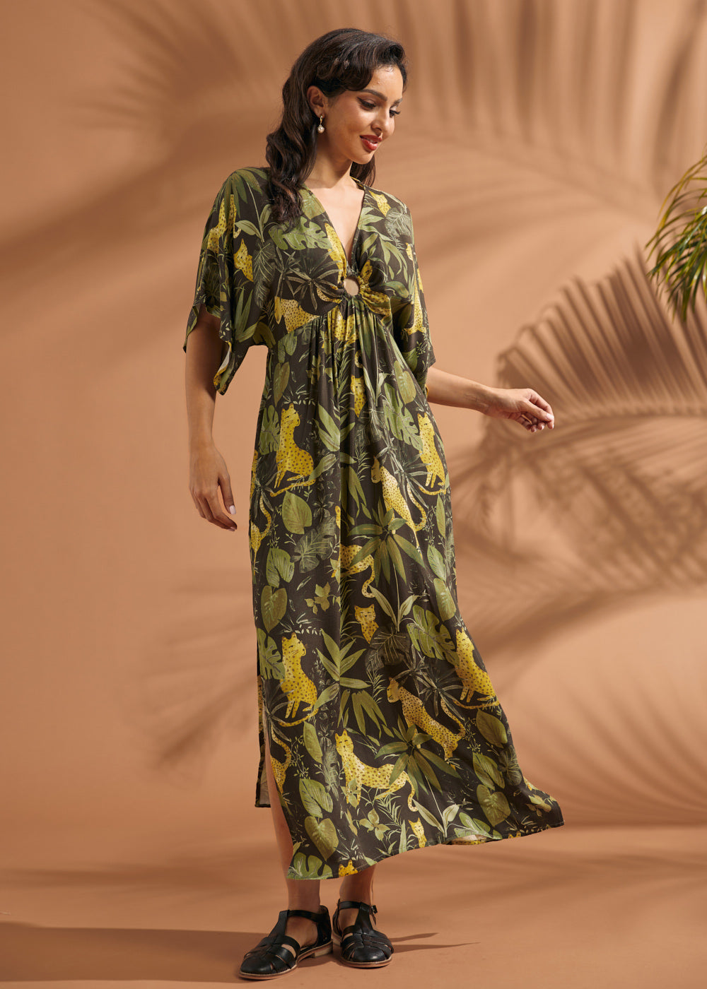 Woman wearing a flowing vintage-inspired jungle print maxi dress with side slit and flutter sleeves.