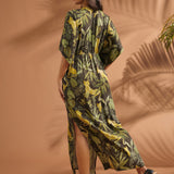 Back view of a woman wearing a tropical print maxi dress with elasticized waist and side slit.