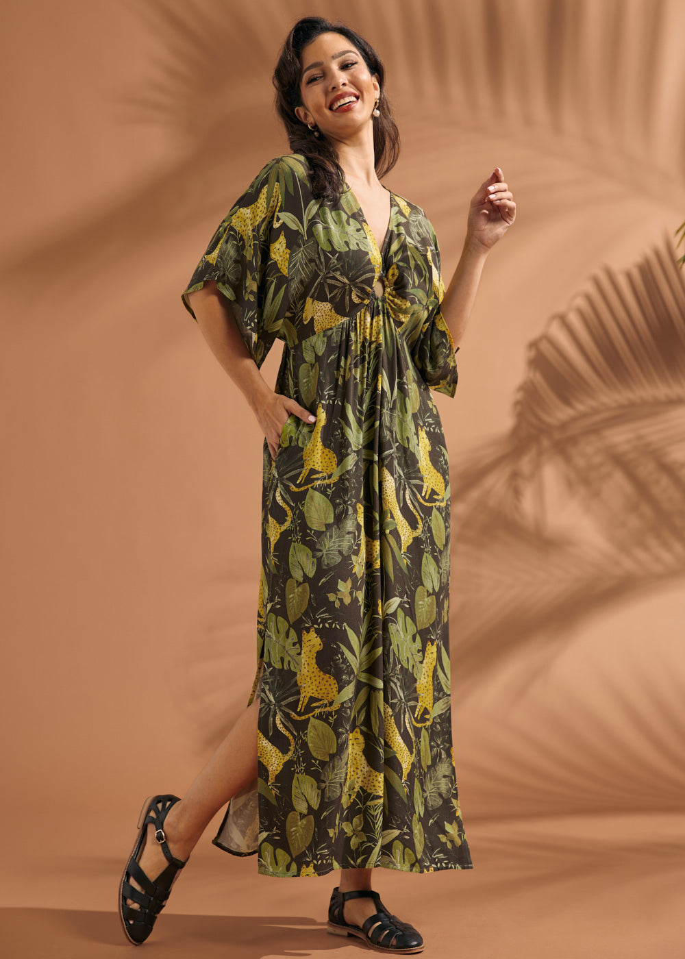 Woman smiling while wearing a relaxed tropical print maxi dress with flutter sleeves.