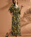 Woman smiling while wearing a relaxed tropical print maxi dress with flutter sleeves.