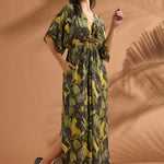 Woman smiling while wearing a relaxed tropical print maxi dress with flutter sleeves.