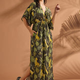 Woman smiling while wearing a relaxed tropical print maxi dress with flutter sleeves.