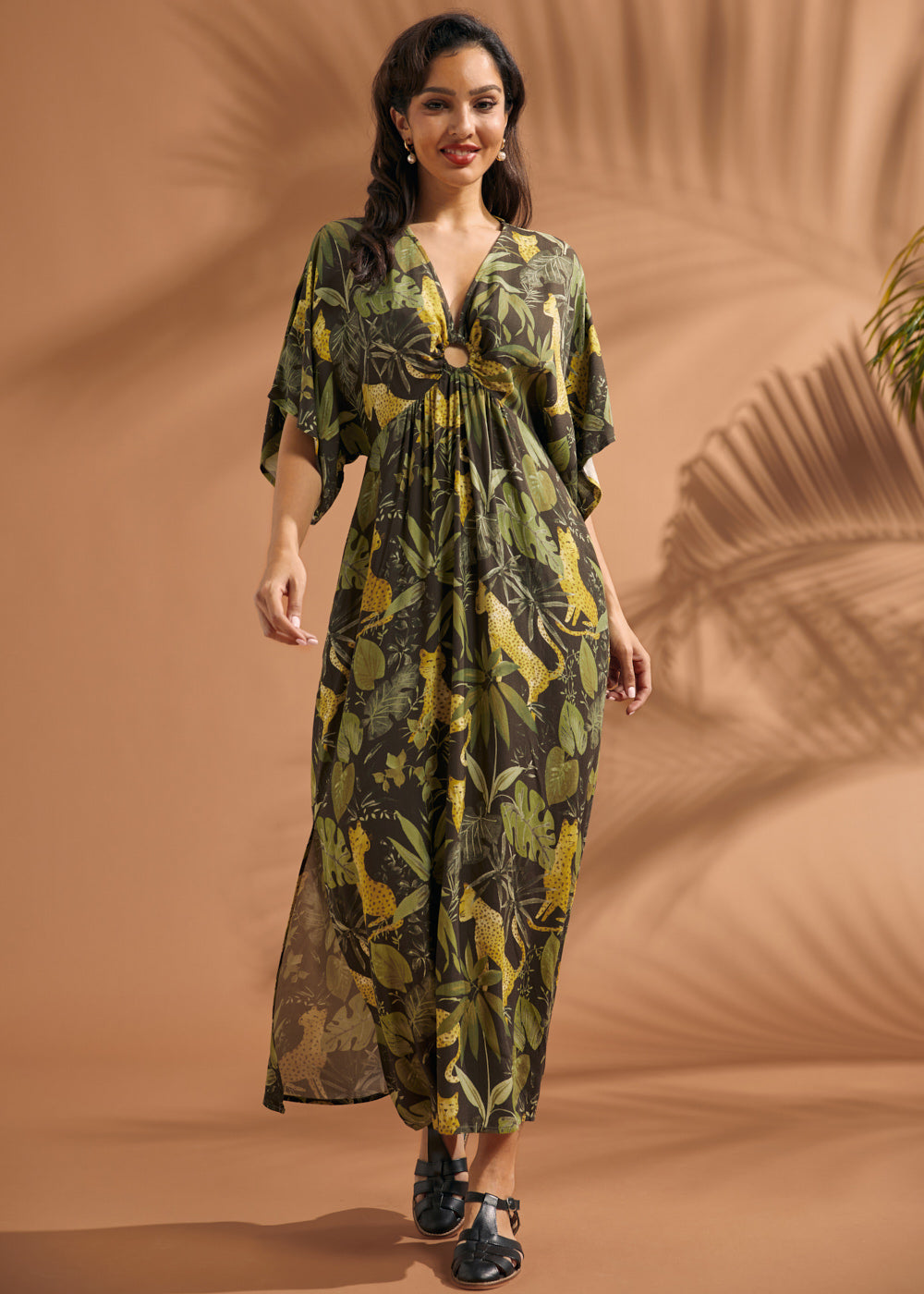 Woman walking in a lightweight jungle print maxi dress with dramatic flutter sleeves and side pockets.