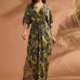 Woman walking in a lightweight jungle print maxi dress with dramatic flutter sleeves and side pockets.
