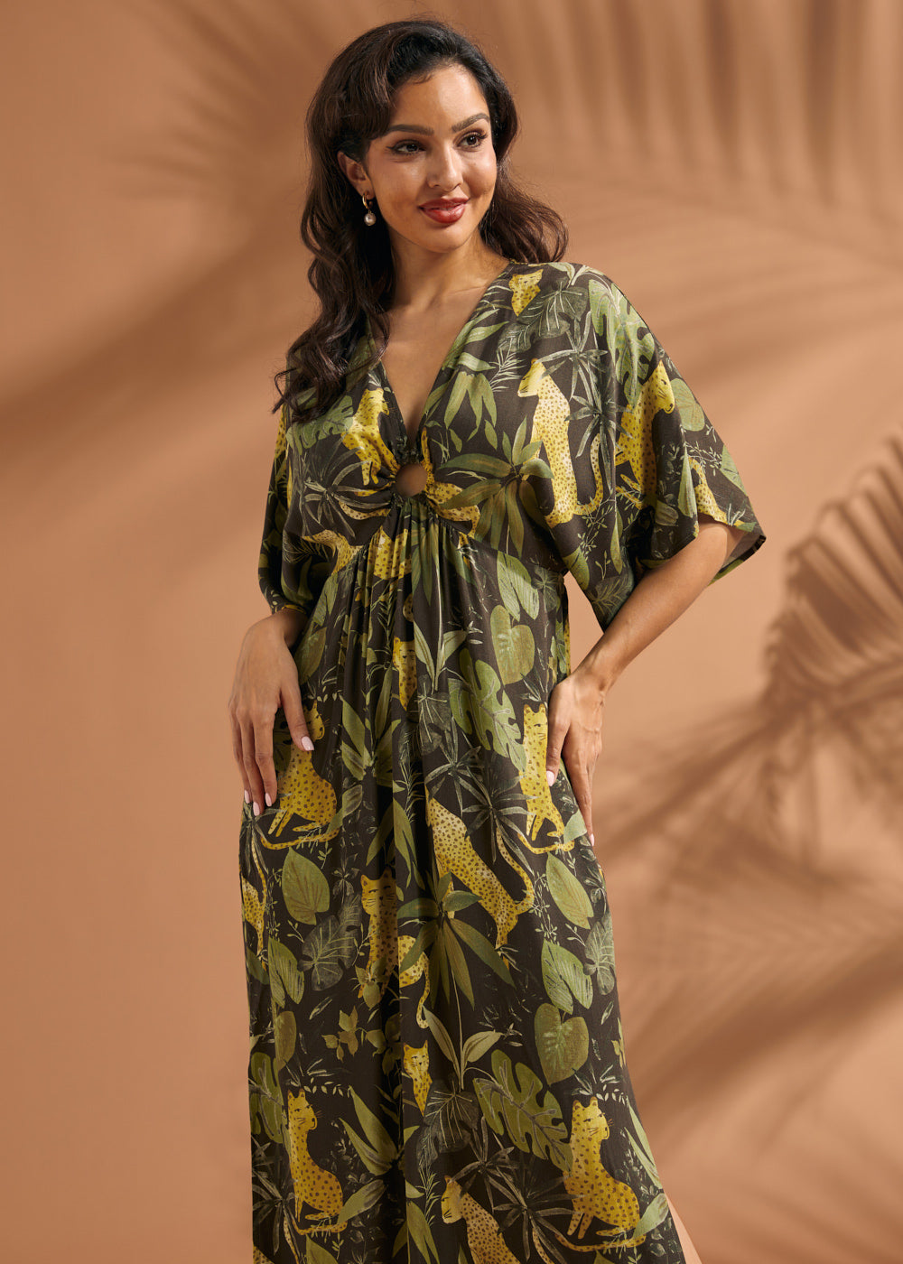 Woman posing in a tropical print maxi dress with front ring detail and flowing silhouette.