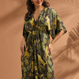 Woman posing in a tropical print maxi dress with front ring detail and flowing silhouette.