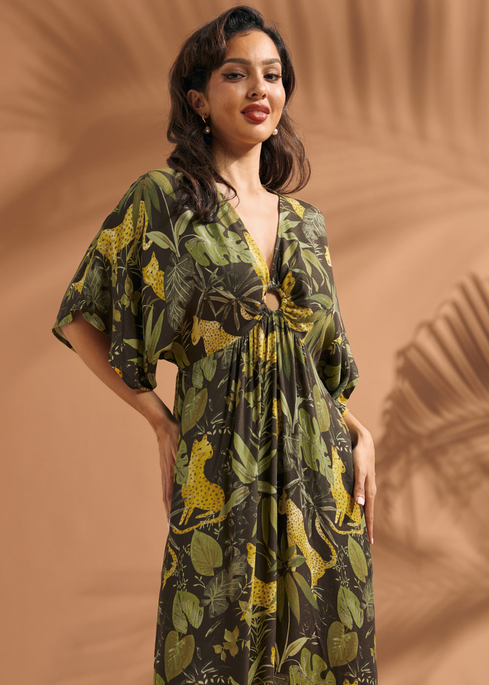 Woman wearing a tropical jungle print maxi dress with flutter sleeves and ring front keyhole detail.