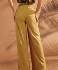Back view of mustard wide leg pants with elastic waistband and welt pocket.