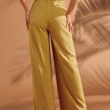 Back view of mustard wide leg pants with elastic waistband and welt pocket.