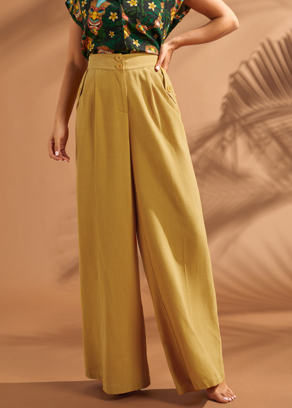 Woman styling wide leg trousers with a printed camp shirt.