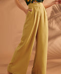 Woman wearing mustard yellow high waisted wide leg linen blend pants with pleats.