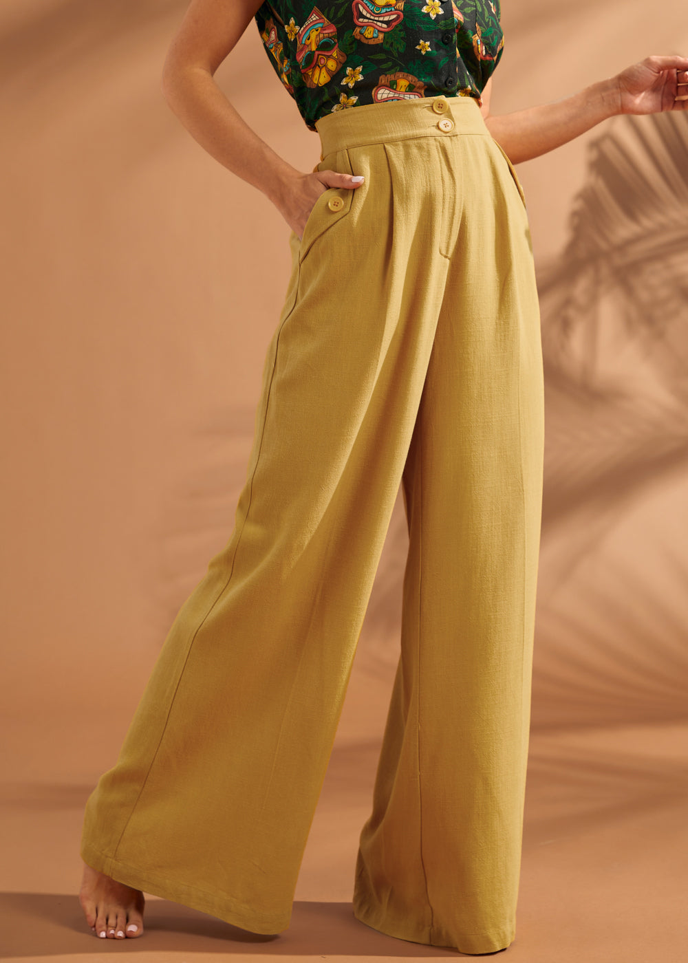 Woman wearing mustard yellow high waisted wide leg linen blend pants with pleats.