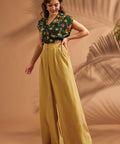 Woman walking in flowing mustard wide leg pants with tailored waistband.