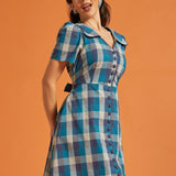 Woman wearing a retro blue checkered cotton dress with short puff sleeves and removable sash belt
