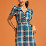 Woman wearing a vintage-inspired blue plaid cotton shirt dress with puff sleeves and oversized collar