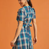 Side view of vintage-inspired blue plaid dress with button-front design and flared skirt