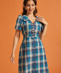Front view of blue plaid fit-and-flare shirt dress featuring fabric-covered buttons and tie waist