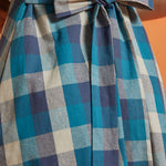 Close-up of back tie belt on blue plaid fit-and-flare dress