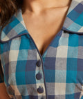 Detail of oversized collar, contrast piping, and fabric-covered buttons on blue plaid dress