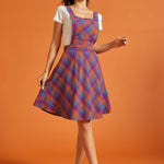 Woman wearing retro-inspired plaid pinafore dress with front bib pocket
