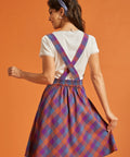 Back view of plaid pinafore dress with crossed straps and elastic waist