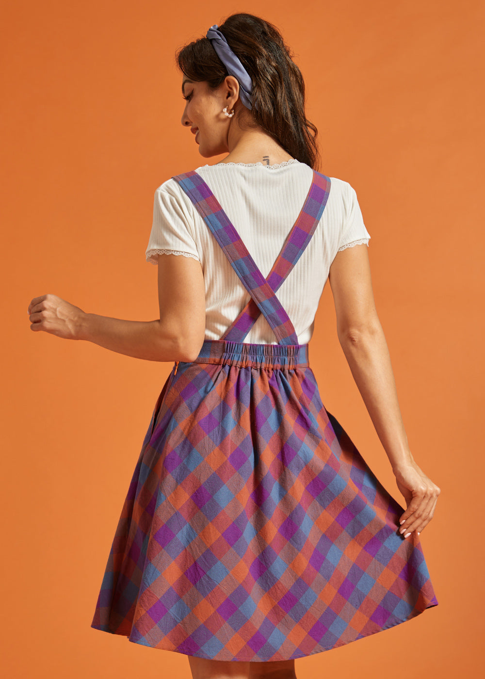 Back view of plaid pinafore dress with crossed straps and elastic waist