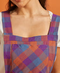 Close-up of square neckline and plaid bib pocket on vintage-inspired pinafore dress