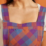 Close-up of square neckline and plaid bib pocket on vintage-inspired pinafore dress