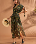 Woman wearing olive green tropical print caftan style maxi dress with tassel sleeves.