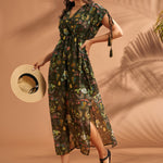 Woman wearing olive green tropical print caftan style maxi dress with tassel sleeves.