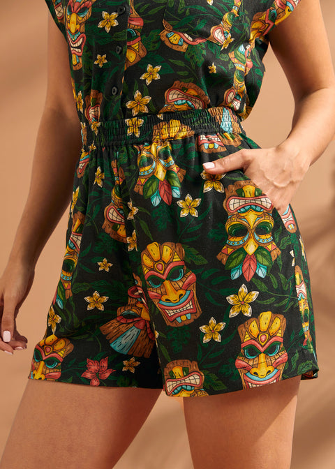 Woman wearing tropical tiki print pull-on shorts with elastic waistband and side pockets.