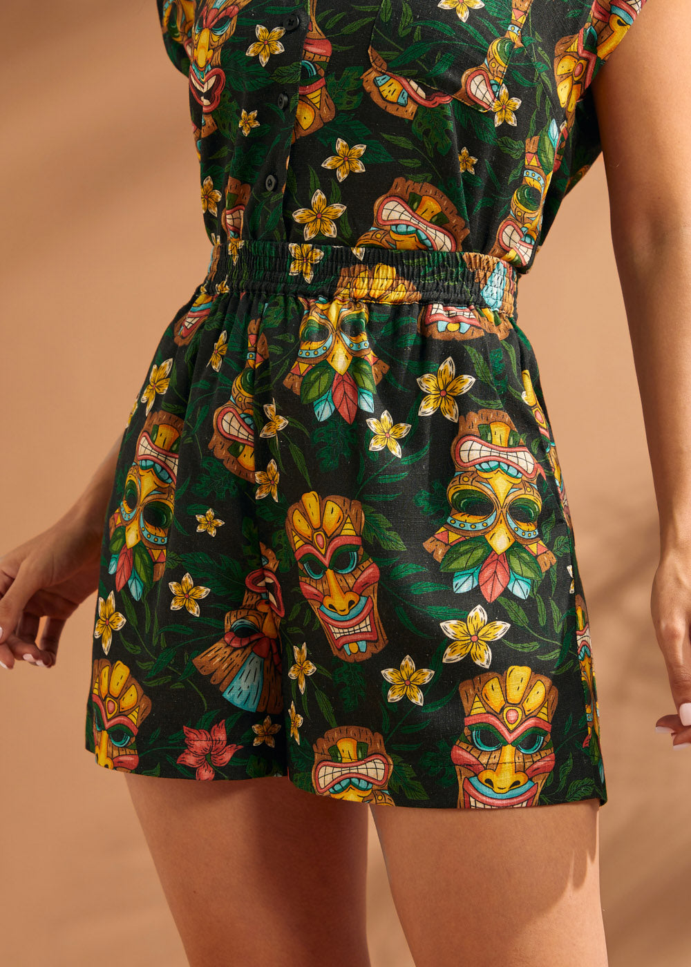 Woman wearing colorful tiki mask print shorts with easy pull-on styling.