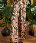 Woman standing with hands in pockets wearing printed palazzo pants.